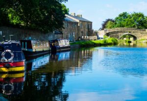 Canal boats moored beside a stone bridge and cottages