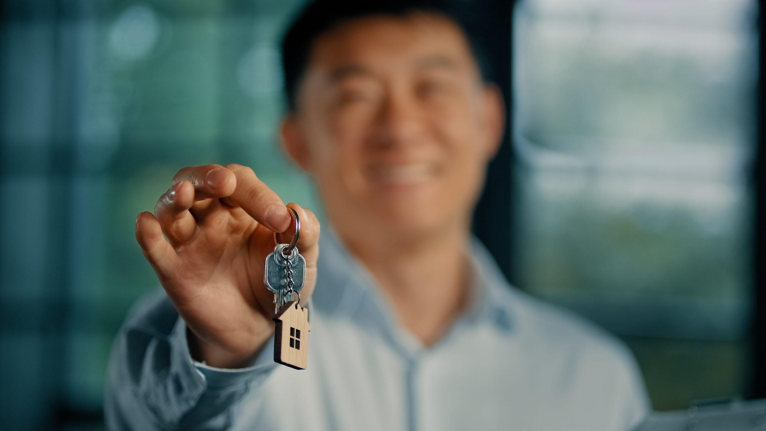 Smiling man holding house keys with a house-shaped keyring